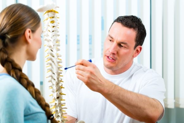Physiotherapeut und Patient besprechen Rückenschmerzen